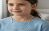 Young girl wearing a silver necklace in a casual indoor setting