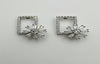 Pair of silver earrings with starburst design on a light gray background