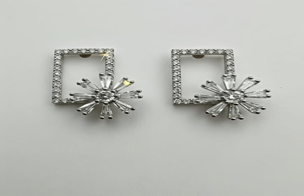 Pair of silver earrings with starburst design on a light gray background
