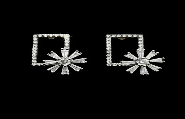 Pair of silver earrings with square frames and starburst designs on a black background
