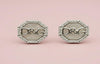 Pair of silver earrings with 'D&G' logo on a pink background