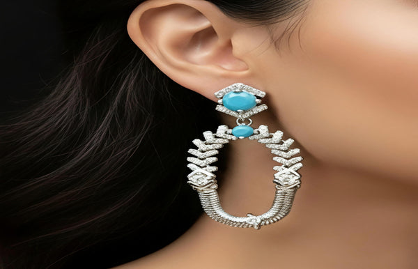 Close-up of an earring with turquoise stone and intricate design on a blurred background