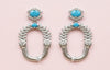 Pair of earrings with turquoise stones on a pink background