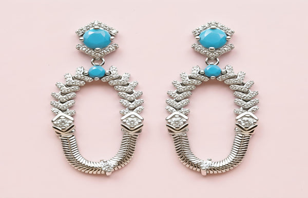 Pair of earrings with turquoise stones on a pink background