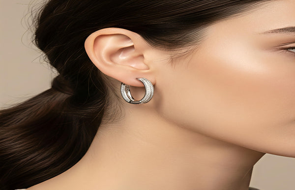 Close-up of a person wearing a silver hoop earring with a neutral background