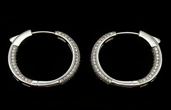 Pair of silver hoop earrings with embedded stones on a black background