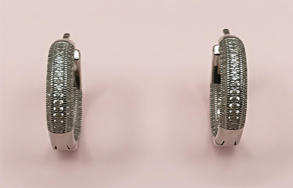 Pair of silver hoop earrings on a pink background