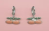 Cherry-themed earrings on a pink background
