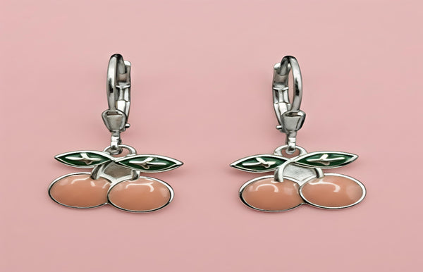 Cherry-themed earrings on a pink background