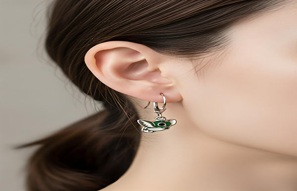 Close-up of a person wearing a green butterfly earring with a neutral background