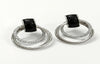 Pair of earrings with black gemstones and silver loops on a white background