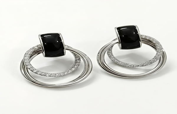 Pair of earrings with black gemstones and silver loops on a white background