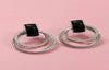 Pair of silver hoop earrings with black gemstones on a pink background