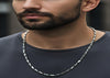 Man wearing a silver chain necklace against a dark background