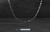 Silver chain necklace on a dark wooden surface with a tag below.