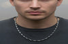 Man wearing a chain necklace against a neutral background
