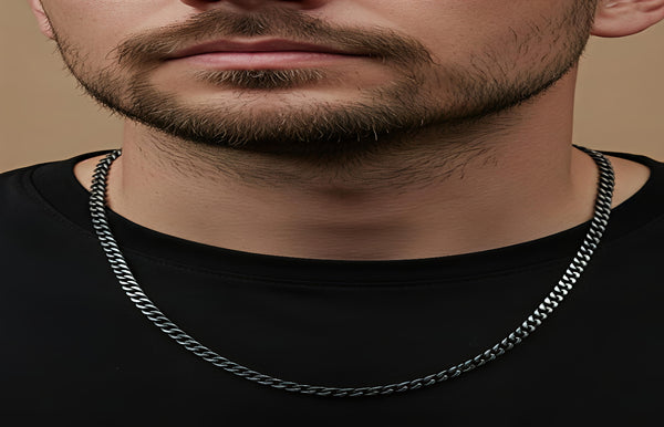 Man wearing a silver chain necklace against a neutral background