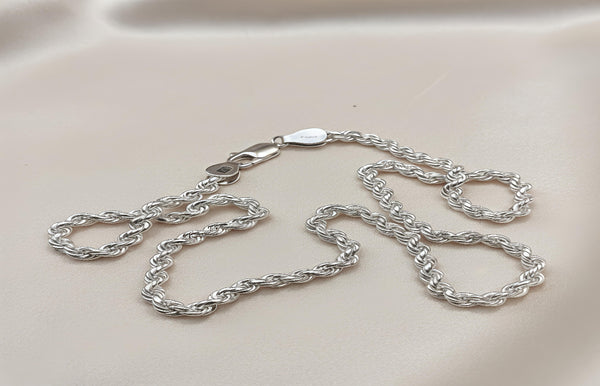 Silver chain necklace on a light beige background
