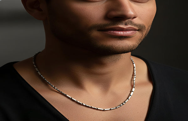 Man wearing a silver necklace against a dark background