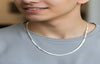 Man wearing a silver necklace against a neutral background