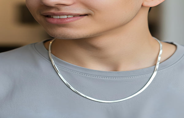 Man wearing a silver necklace against a neutral background