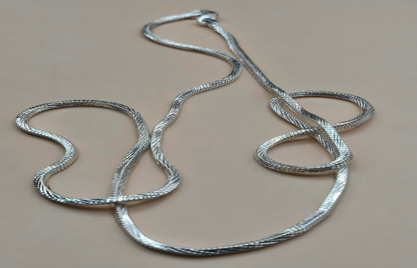 Silver snake chain necklace on a beige background