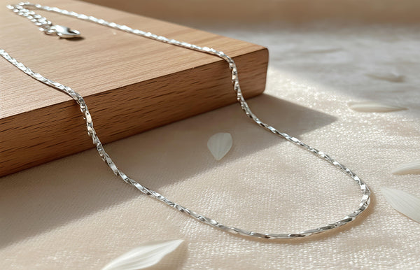 Silver necklace on a wooden block with a soft background