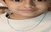 Close-up of a child wearing a silver necklace with a neutral background
