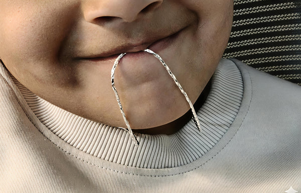 Close-up of a person wearing a silver hoop earring.
