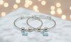 Silver bangle with blue elephant charms on a soft surface with blurred lights in the background